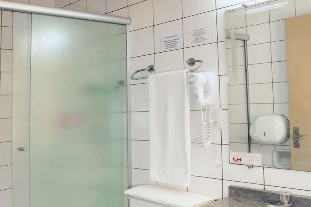 A modern bathroom with a glass shower enclosure, a white toilet, a granite countertop sink, and a mirror above the sink.