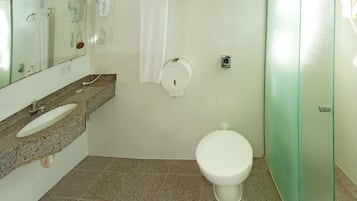 Une salle de bain équipée d’un lavabo, d’un miroir, d’un porte-serviettes, de toilettes et d’une douche à parois en verre.