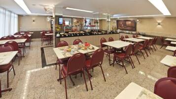 A dining area with tables and chairs, a buffet counter, and a large painting on the wall.