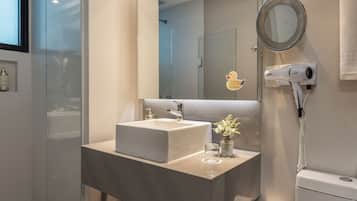 A modern bathroom with a large mirror, a white sink, and a hairdryer mounted on the wall.