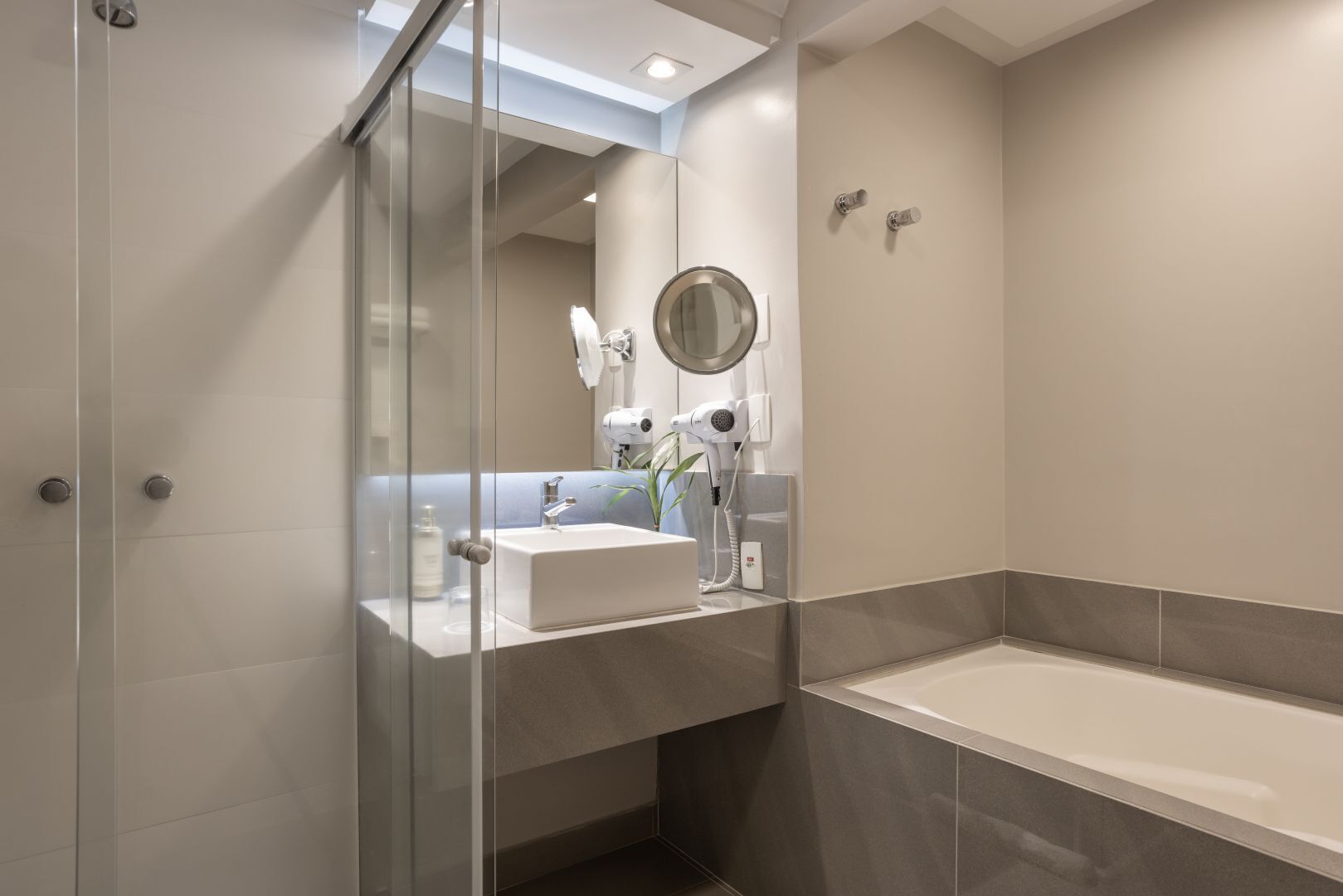 Un baño moderno con cabina de ducha de vidrio, un lavamanos con espejo y una bañera independiente.