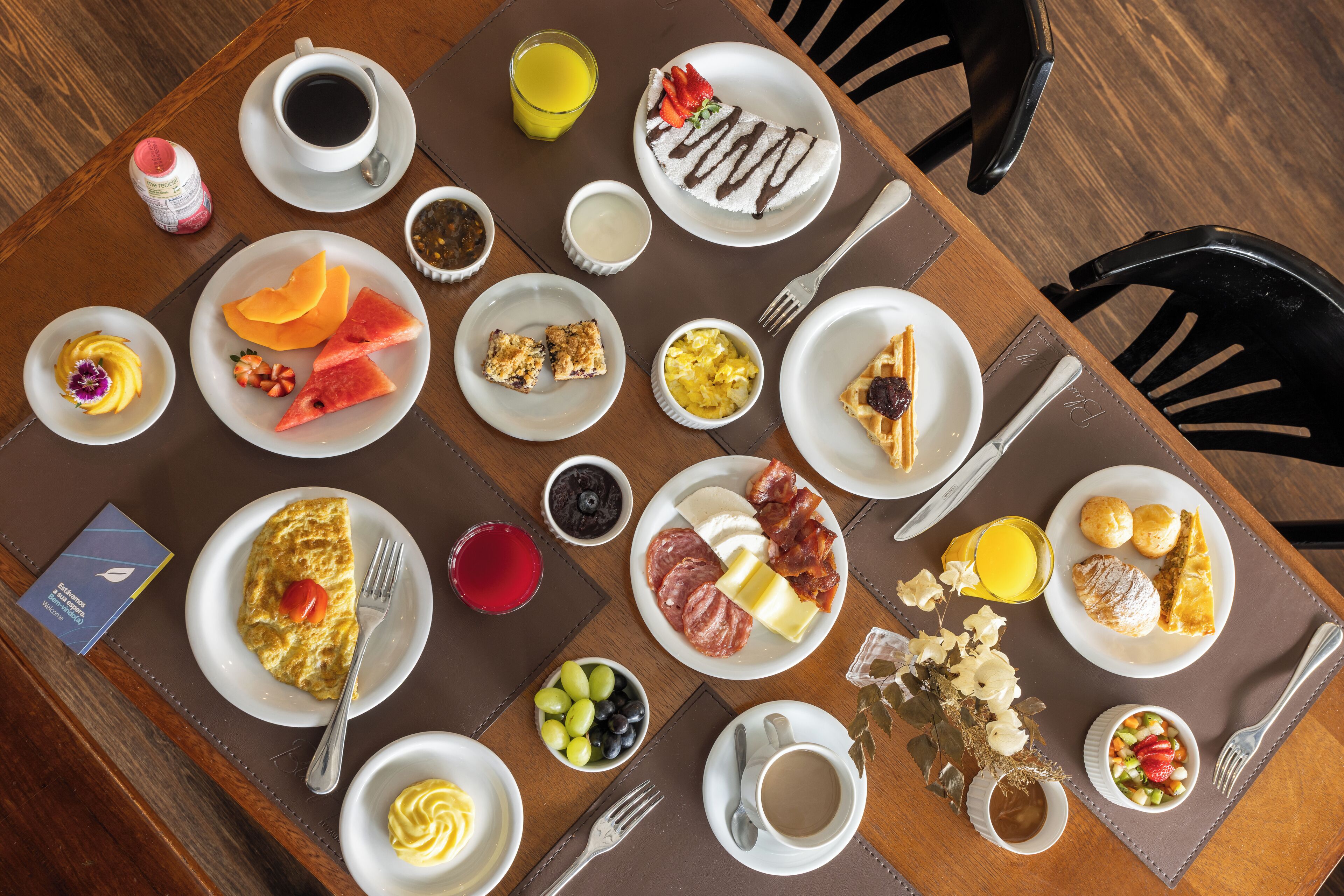 A breakfast buffet with various dishes, drinks, and condiments.