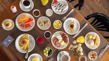 A breakfast buffet with various dishes, drinks, and condiments.