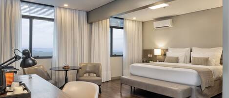 Una habitación de hotel moderna con una cama grande, un escritorio con teléfono, una silla y una mesita.