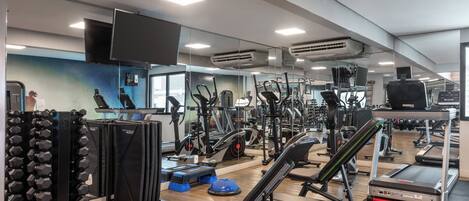 Une salle de sport équipée de divers appareils d’entraînement, notamment des tapis de course, des appareils de musculation et des poids libres.