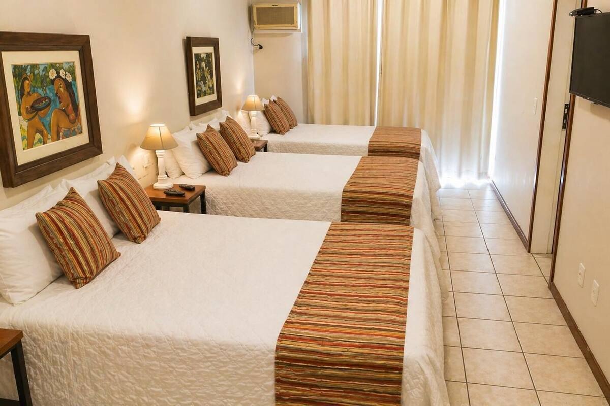 A hotel room with two beds, a TV, and artwork on the walls.