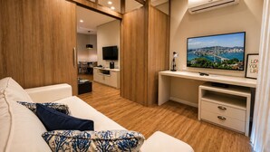 A modern interior with a sofa, TV, desk, and kitchen area. - Hotel Ingleses Holiday (Florianopolis)