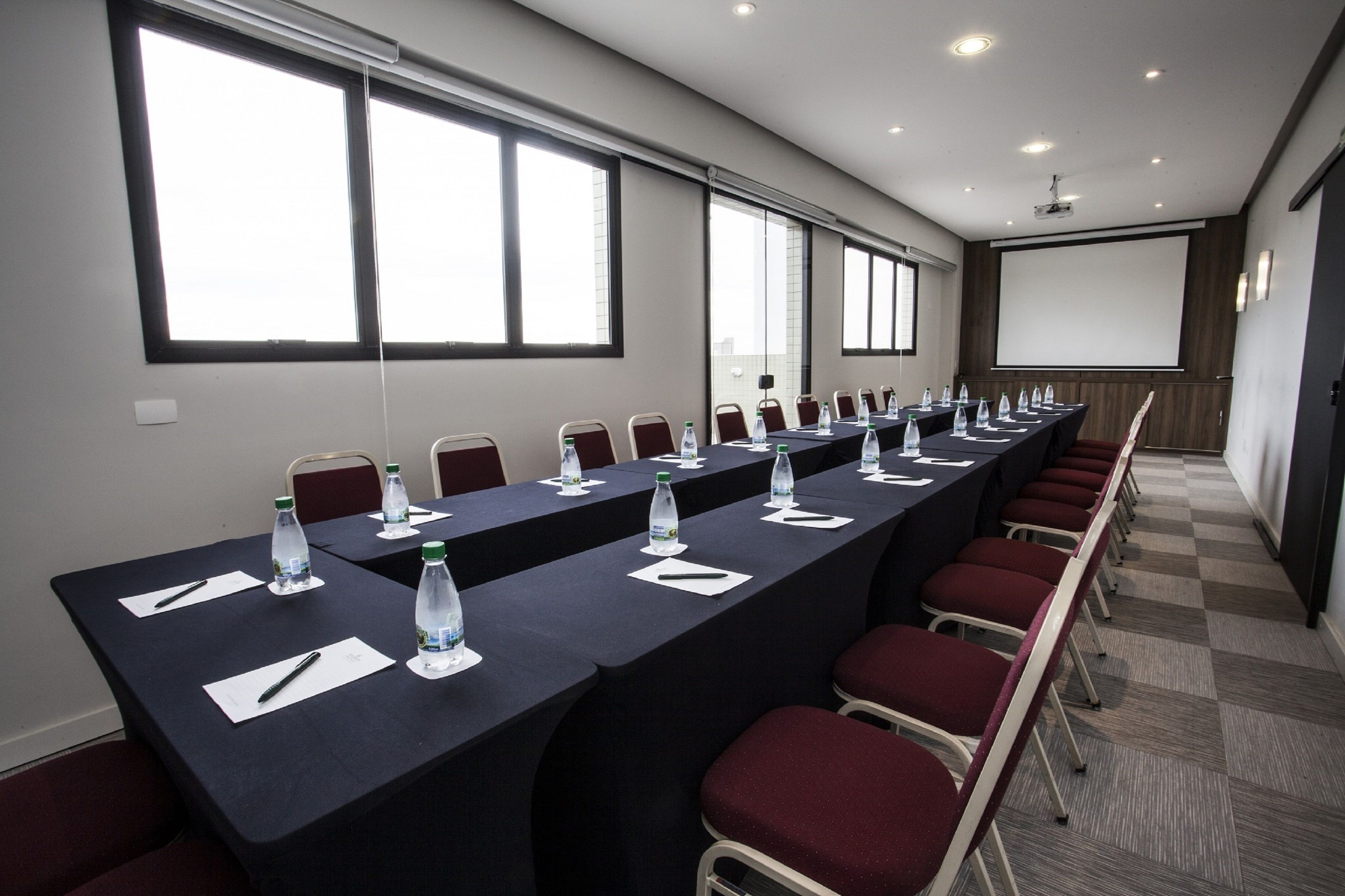 A conference room with a long table, chairs, water bottles, and name cards.