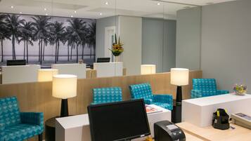 A modern reception area with a computer, desk, chairs, and a decorative wall mural.