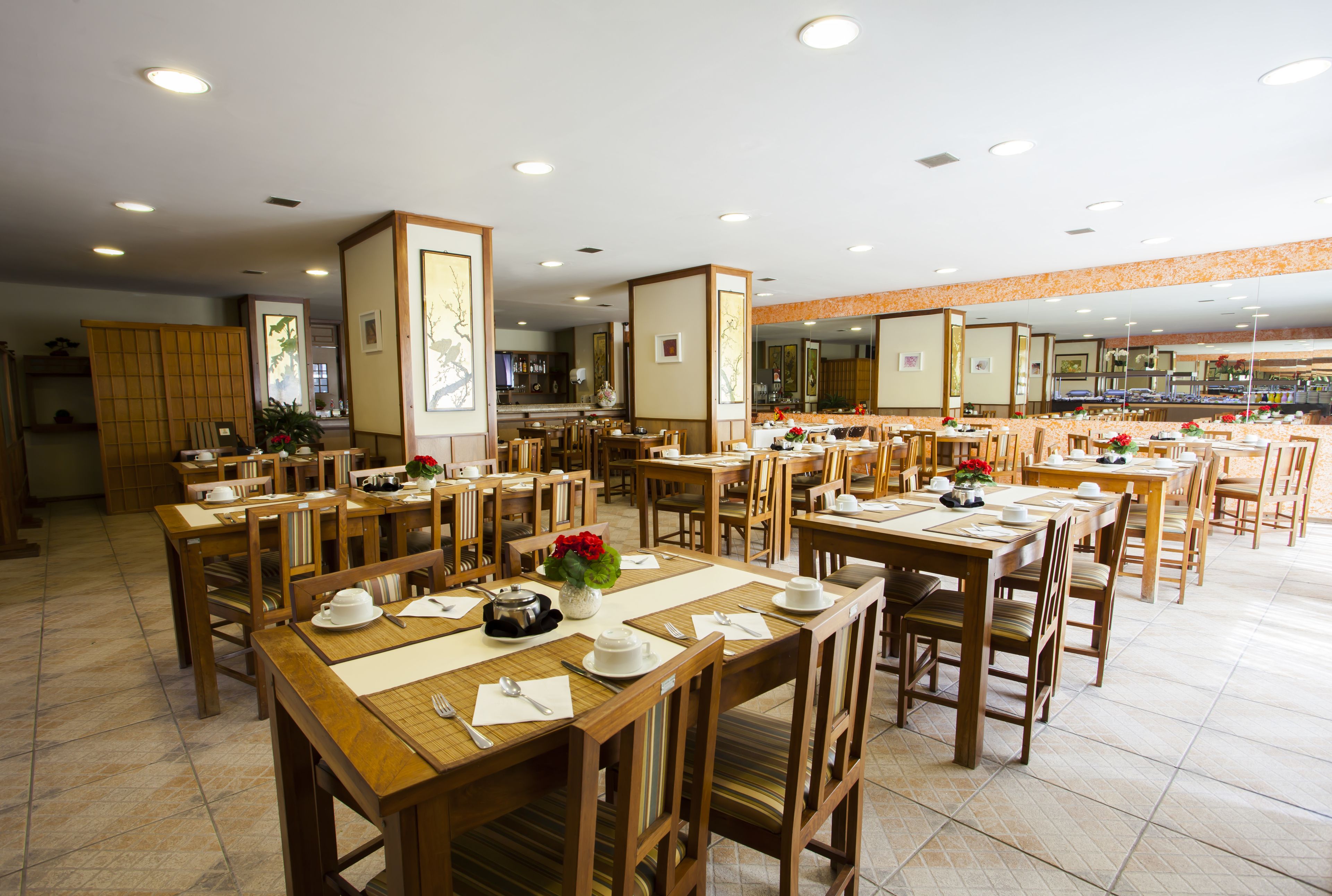 Un comedor amplio con varias mesas y sillas de madera, dispuestas al estilo bufé.