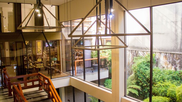 Un intérieur moderne avec de grandes fenêtres, un escalier et des luminaires suspendus.