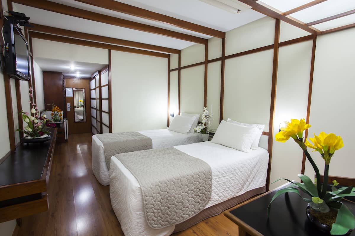 Une chambre d’hôtel avec deux lits, un bureau et une télévision.