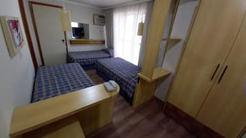 Habitación de hotel compacta con dos camas, un escritorio, un teléfono y un armario.