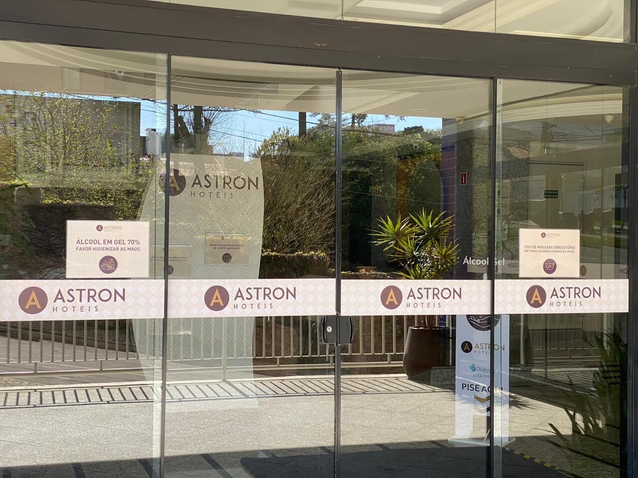 A hotel entrance with glass doors and multiple signs advertising the hotel and its amenities.