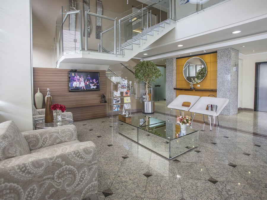 Eine moderne Lobby mit einem Glastisch, gemusterten Sofas, einem Fernseher, einer Pflanze und einer Treppe.