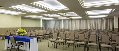 A conference room with rows of chairs, a table with a blue tablecloth, and a floral centerpiece.
