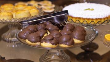 A dessert display with various pastries and a cake on a glass stand.