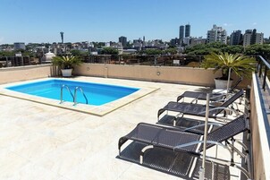 Una piscina al aire libre, sillones reclinables de piscina