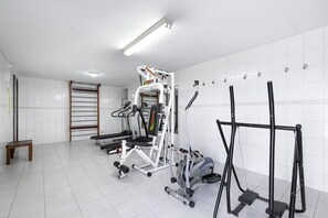 A gym with various exercise equipment, a bench, and a towel rack. - Hotel Flat Petras (Curitiba)