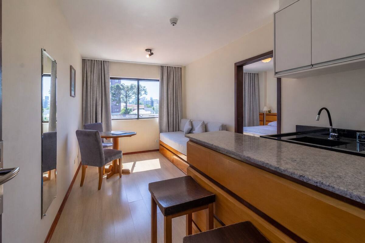A modern kitchen with a built-in sink, a dining area with a table and chairs, and a seating area with a bench.
