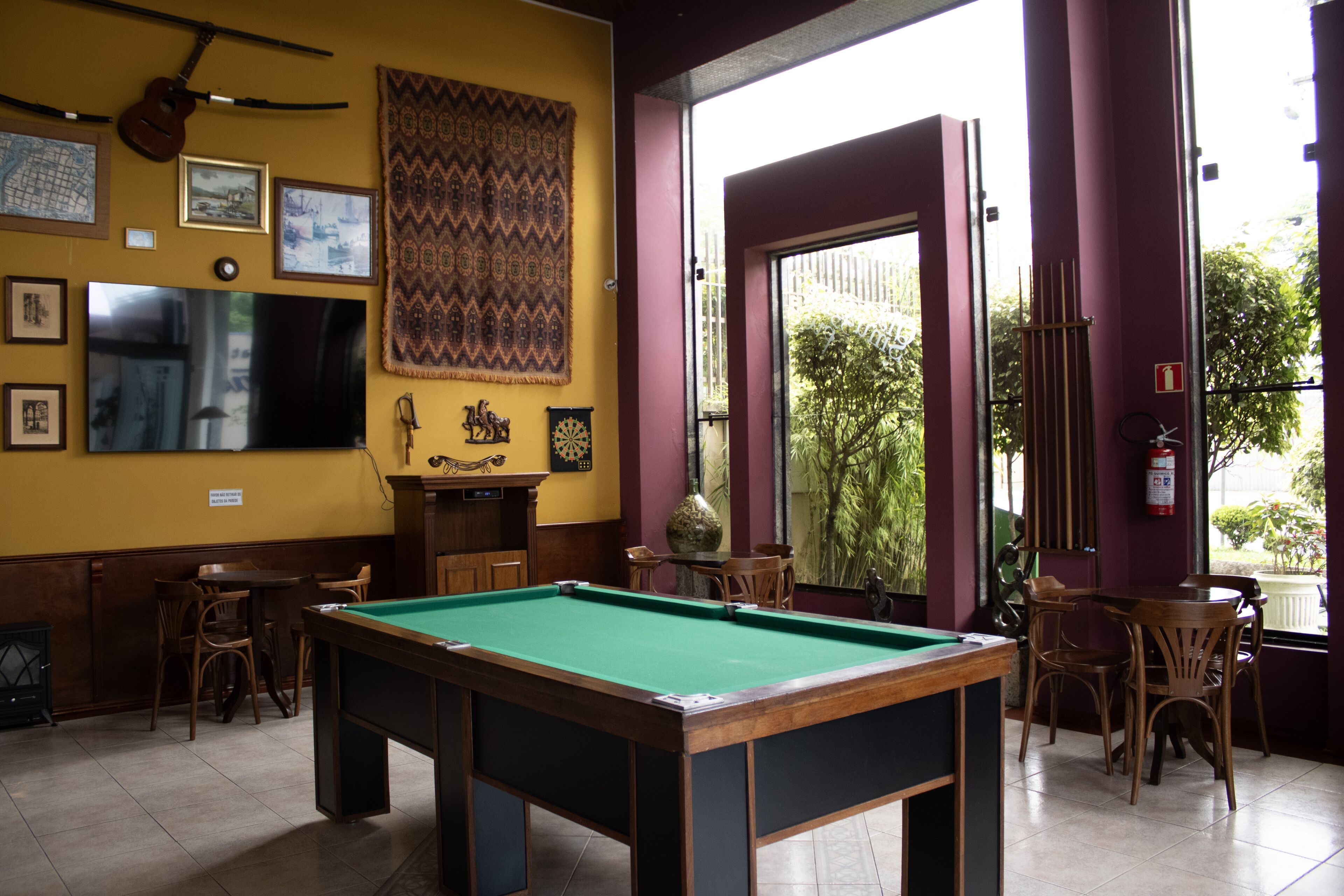 Una sala de billar con mesa de pool, sillas y televisor.