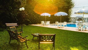 A backyard with a pool, outdoor furniture, and a well-maintained lawn. - Foz Presidente Economic Hotel (Foz do Iguaçu)