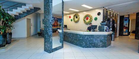 A modern reception area with a marble counter, a staircase, and decorative wreaths on the wall.