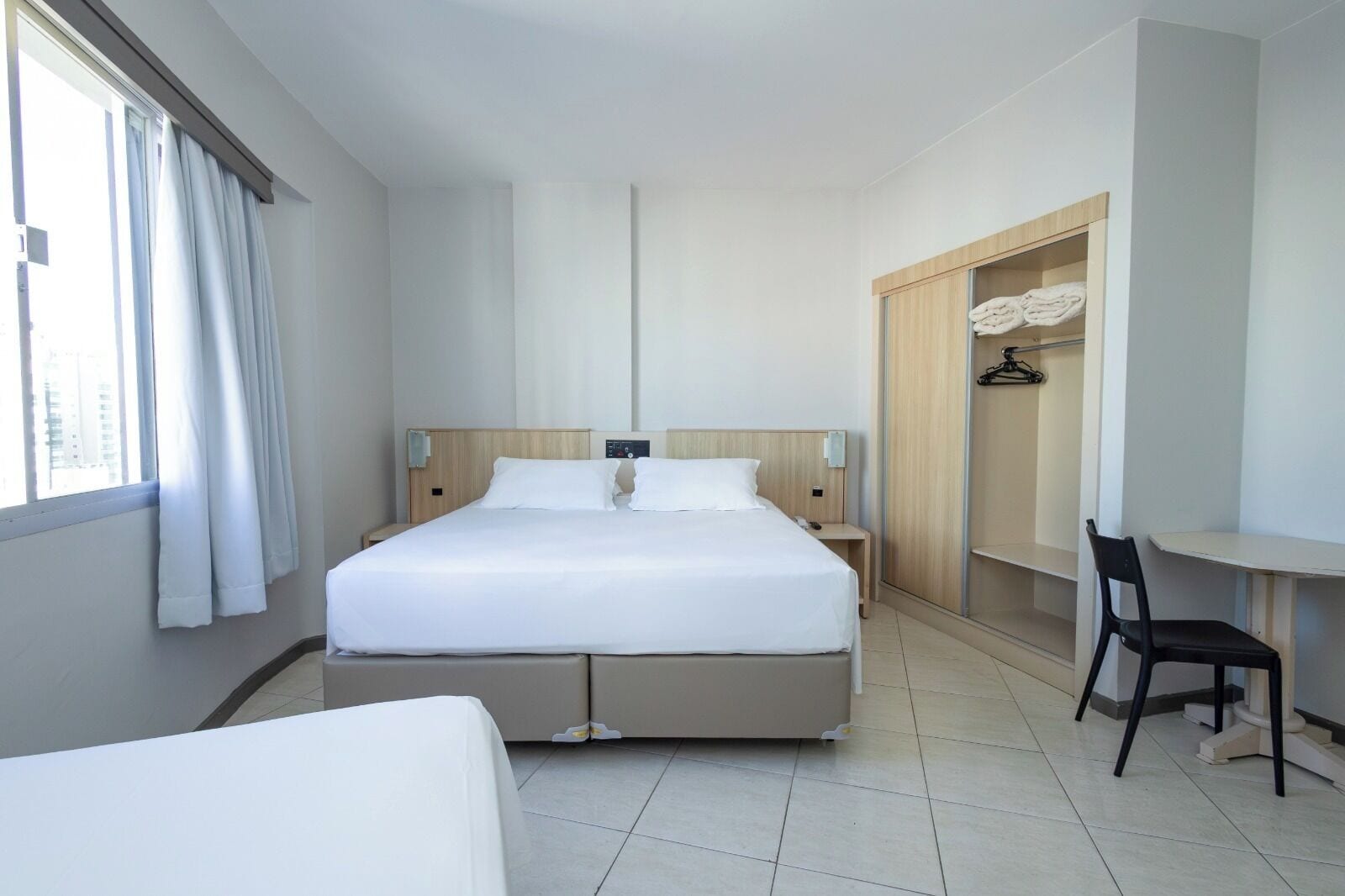 Una habitación de hotel con una cama grande, un escritorio, una silla y un armario.