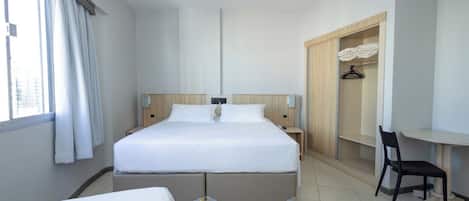 Una habitación de hotel con una cama grande, un escritorio, una silla y un armario.