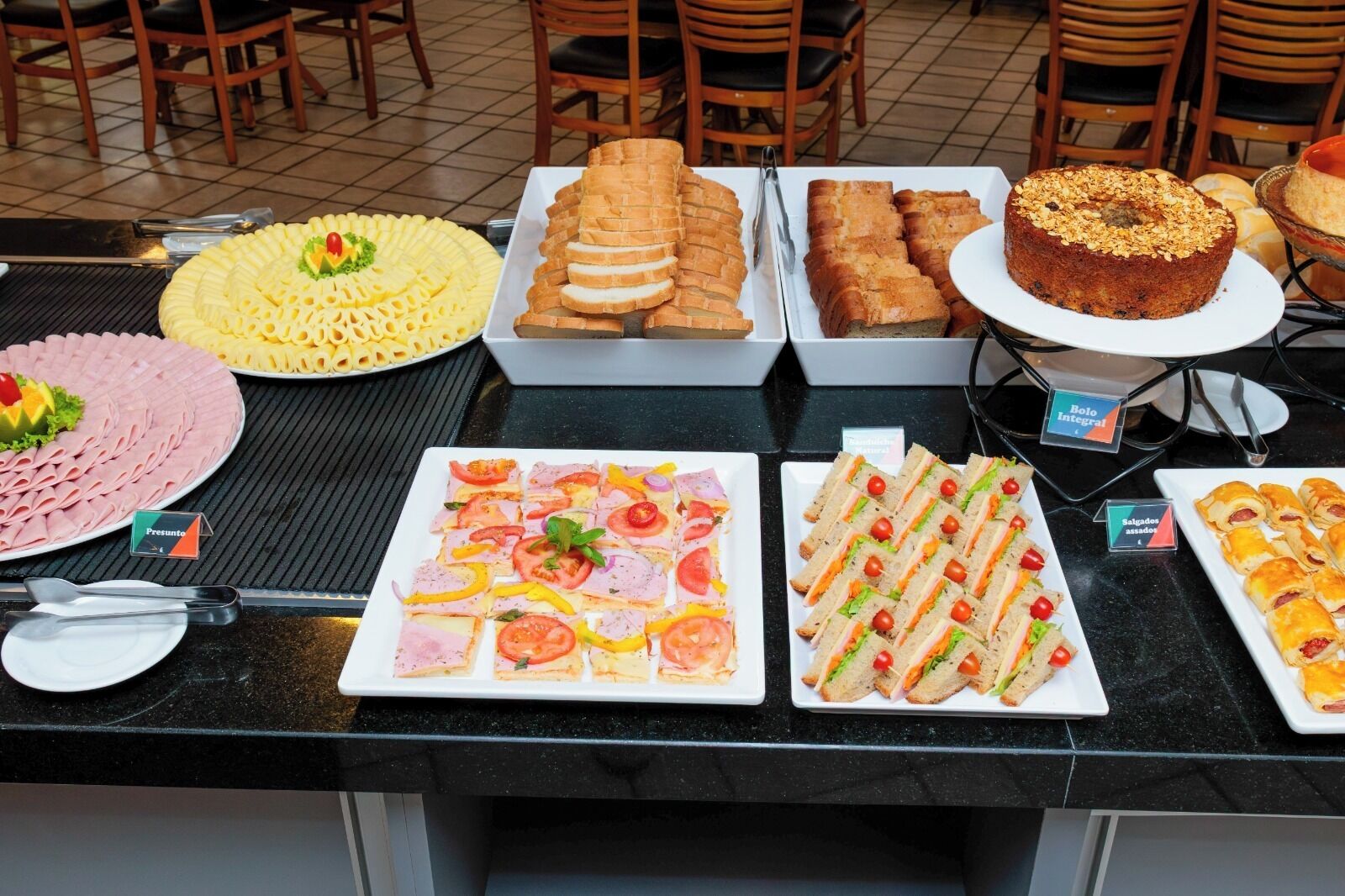 A buffet with various food items including sandwiches, pastries, and a cake.