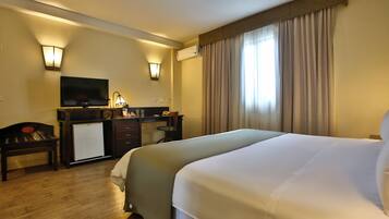 Habitación de hotel con una cama grande, un escritorio con televisor y un minibar.