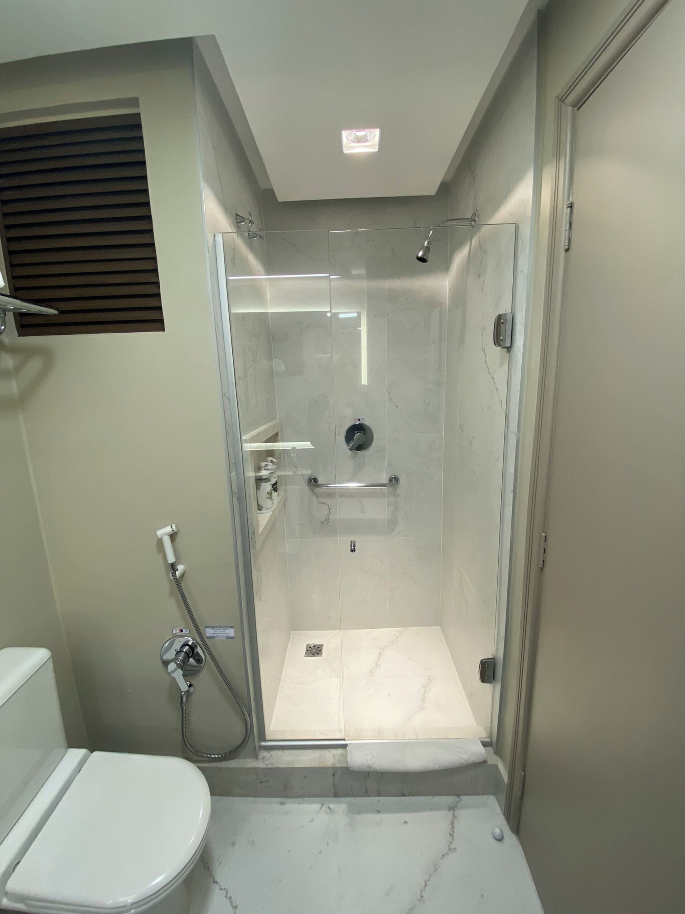 A small, modern bathroom with a glass-enclosed shower, a toilet, and a sink.