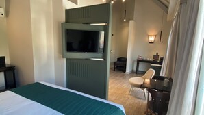A hotel room with a large bed, a television, a desk with a chair, and a ceiling with exposed beams. - Transamerica Executive Curitiba Batel (Curitiba)