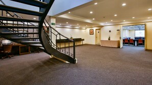 A spacious lobby with a curved staircase, a reception desk, and a conference room with chairs and a screen. - Transamerica Executive Curitiba Batel (Curitiba)
