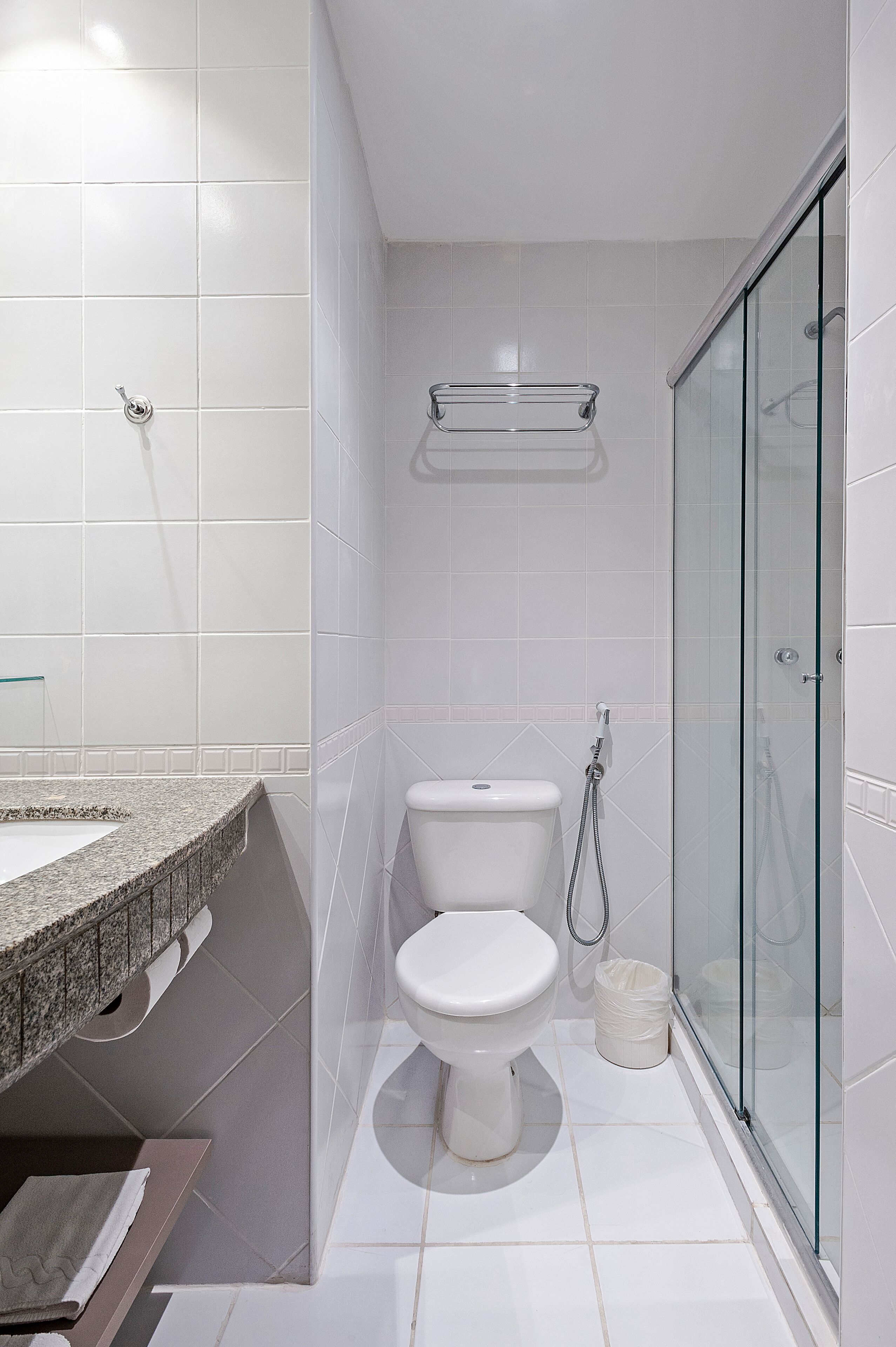 Un baño moderno con cabina de ducha de vidrio, inodoro y lavamanos con encimera de granito.