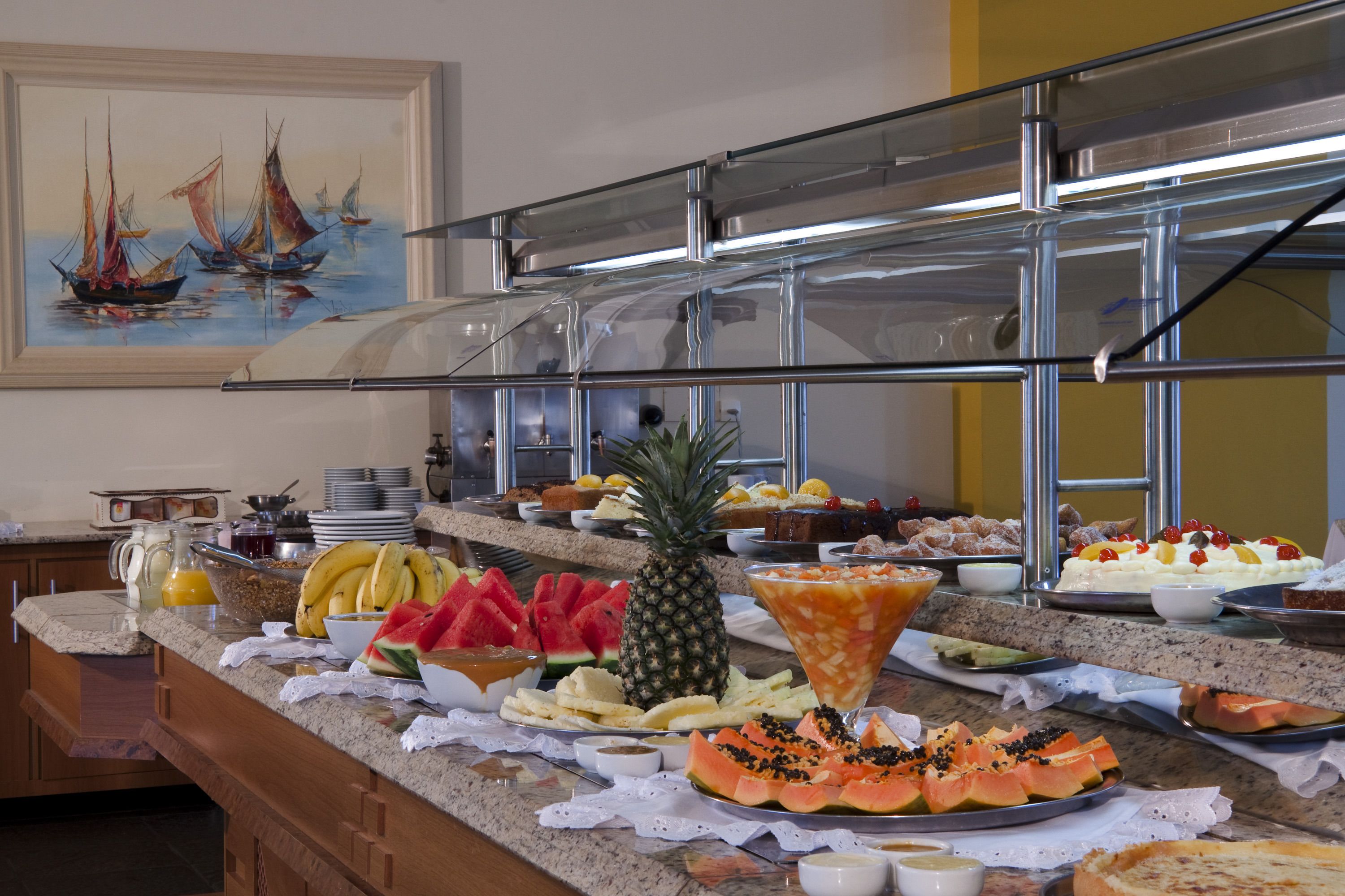A buffet with various fruits, pastries, and beverages.