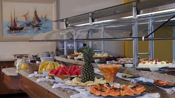 A buffet with various fruits, pastries, and beverages.