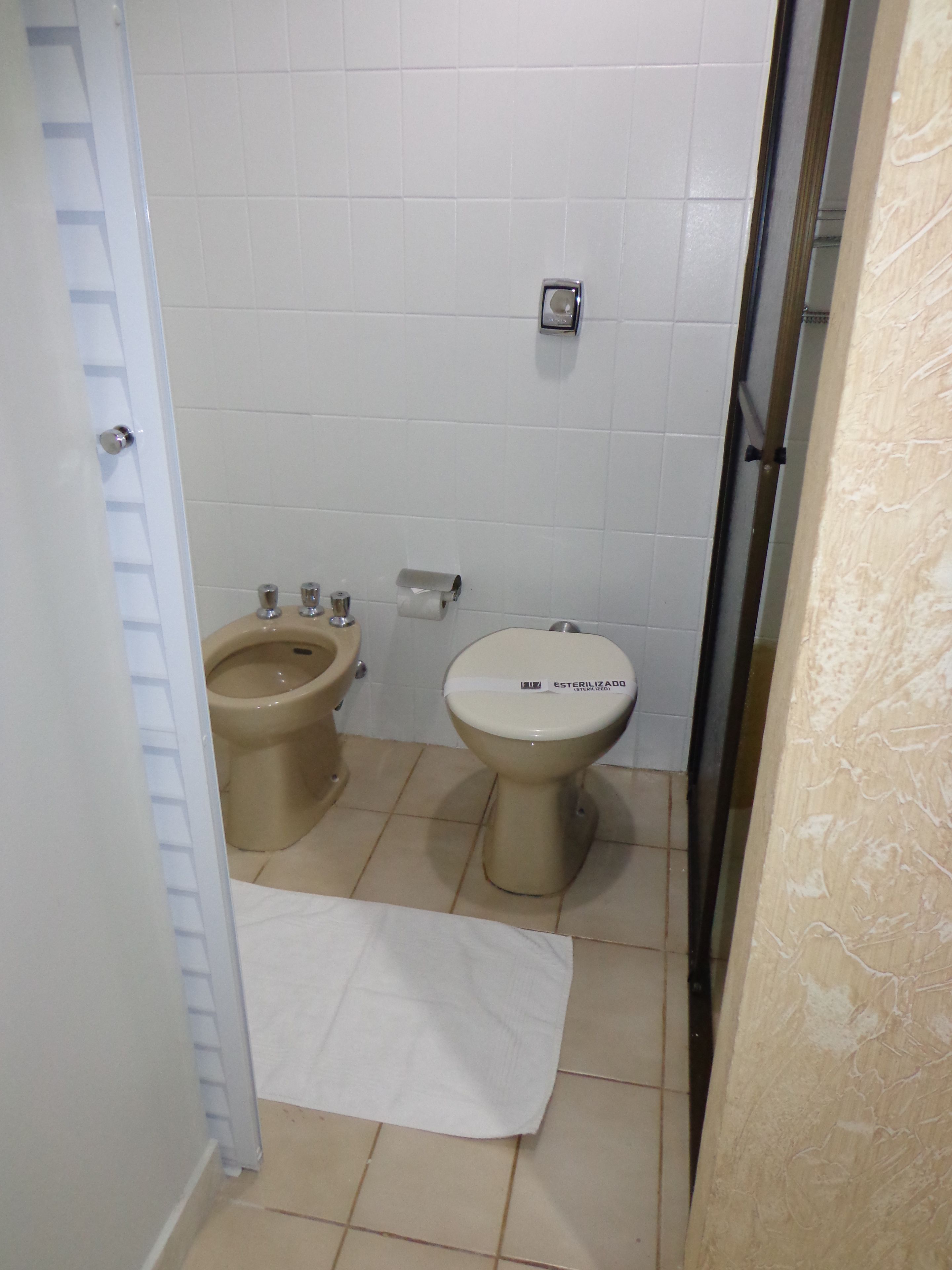 A small bathroom with a toilet, bidet, and a towel on the floor.