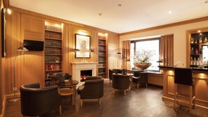 Een ruime woonkamer met een open haard, boekenkasten, een televisie en een barhoek.