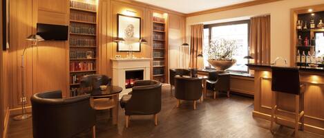 A spacious living room with a fireplace, bookshelves, a television, and a bar area.