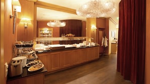 Een ontbijtruimte van een hotel met een buffet, houten kasten en een kroonluchter.