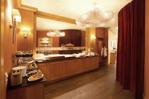Un'area colazione in hotel con buffet, mobili in legno e un lampadario.