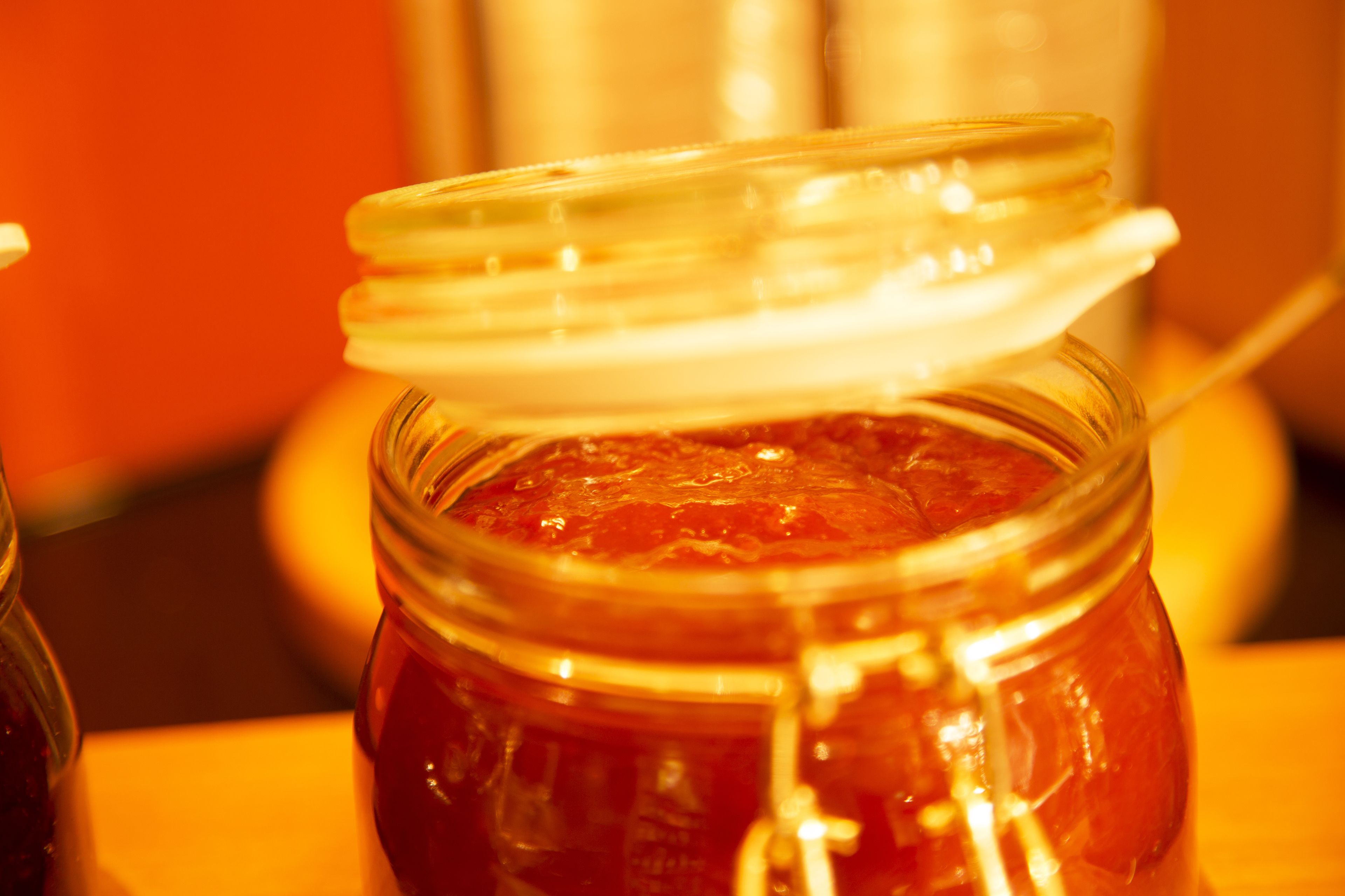 A glass jar with a metal clasp lid containing a red substance, possibly jam or preserves.