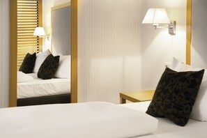 Une chambre d’hôtel avec un lit, une table de chevet, une lampe et un miroir.