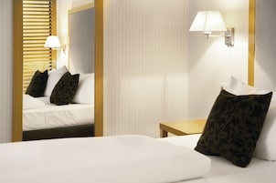 Una camera d'albergo con un letto, un comodino, una lampada e uno specchio.