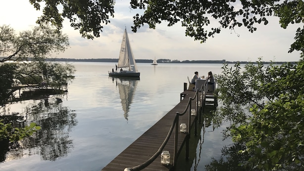 A wooden dock extending into calm water with a sailboat anchored nearby. - Flair Hotel Deutsches Haus (Arendsee)