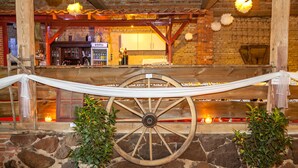 A rustic interior with a wooden bar, stone walls, and a large wooden wheel. - Flair Hotel Deutsches Haus (Arendsee)