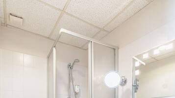 Un baño moderno con ducha de vidrio, un lavabo blanco y un inodoro.