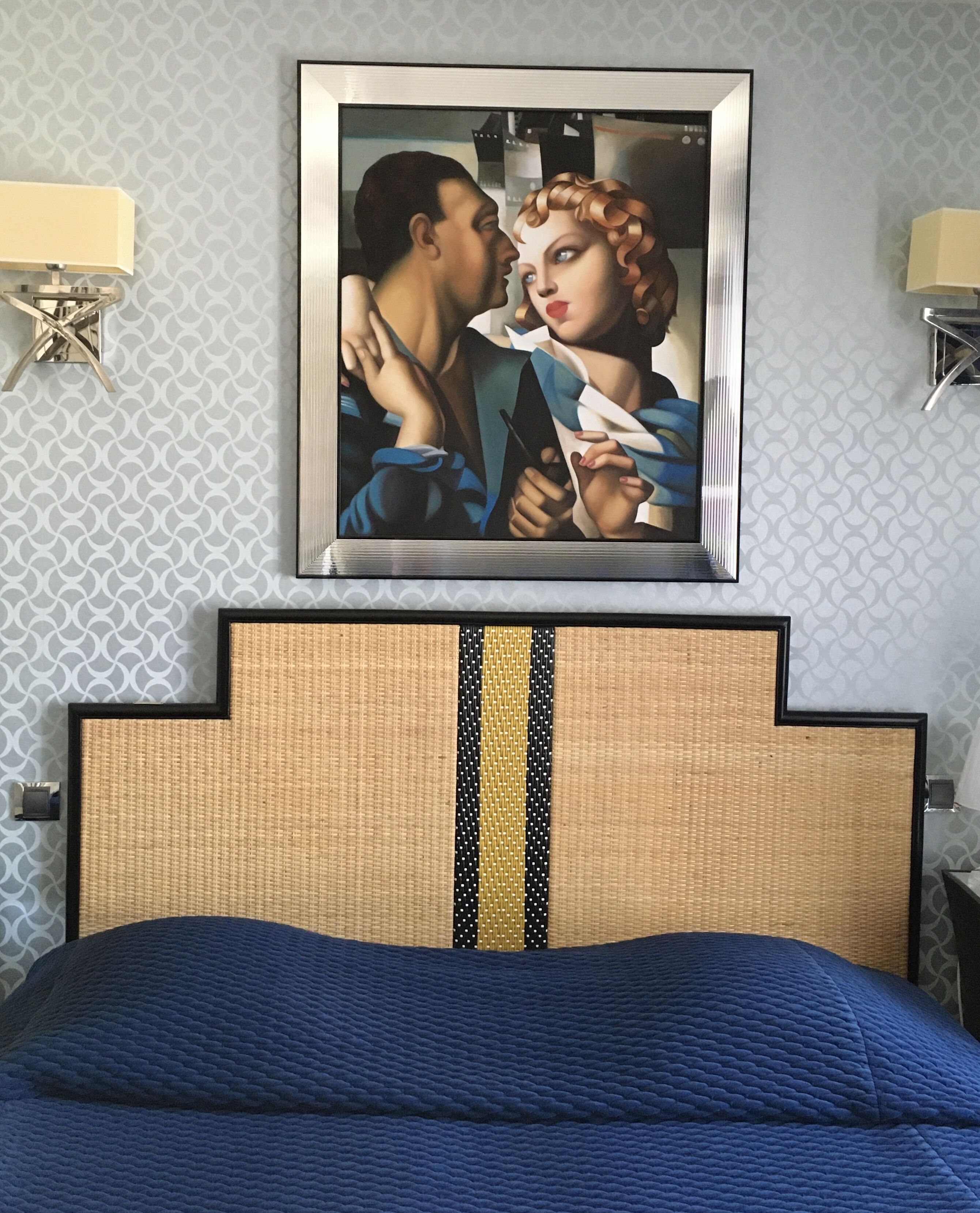 Ein Hotelzimmer mit einem Bett, einem gerahmten Kunstwerk darüber und einer Wand mit Muster.