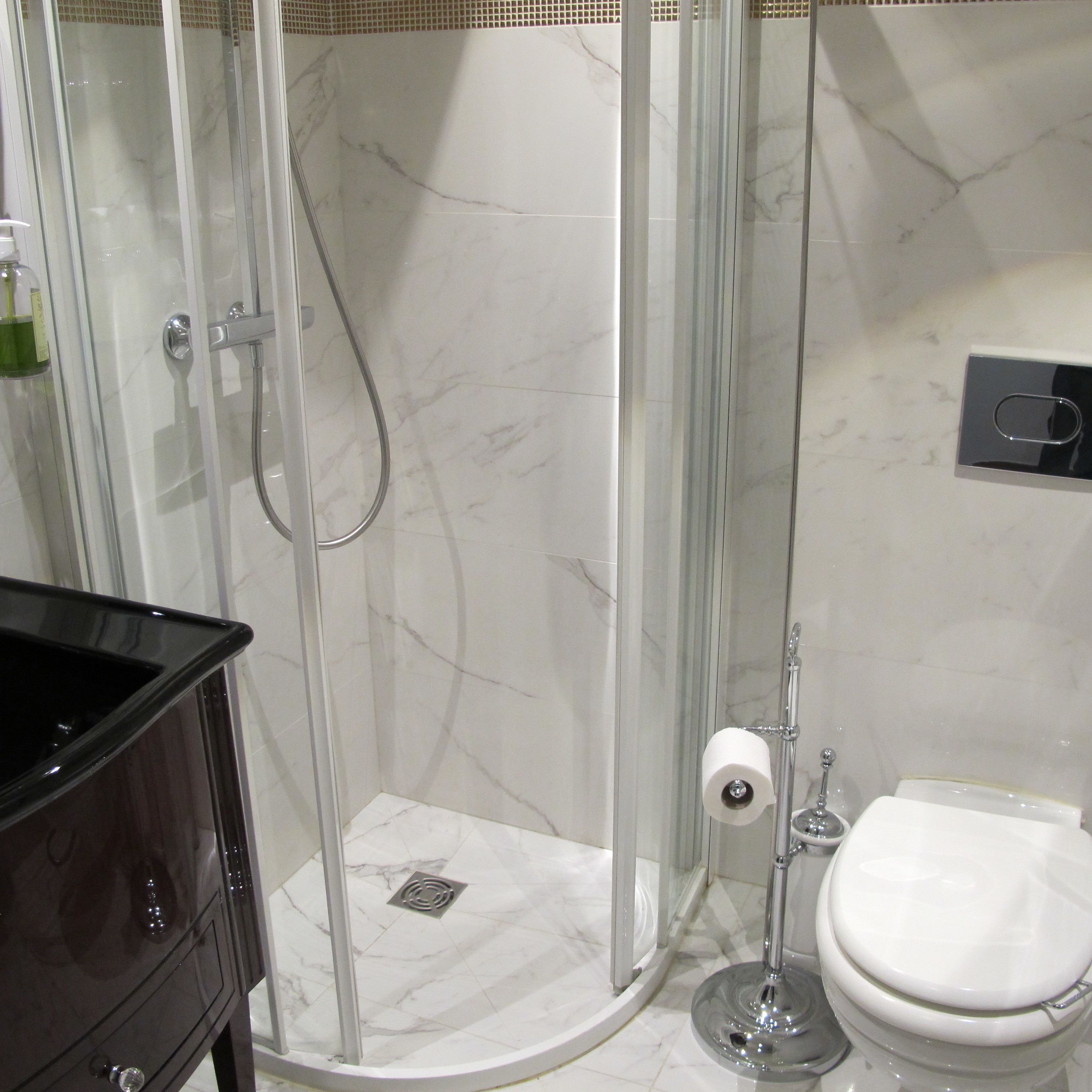 A bathroom with a glass-enclosed shower, a toilet, and a dark-colored vanity.